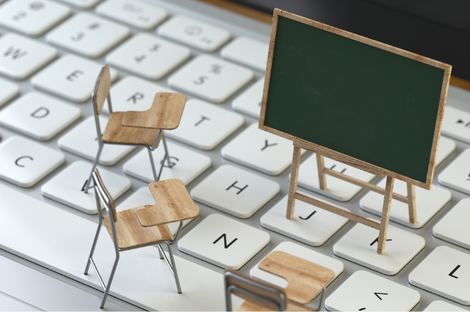 Auf einer Tastatur stehen eine
Miniatur-Tafel und drei Miniatur-
Stühle, was an einen Ort des Lernens
erinnert.